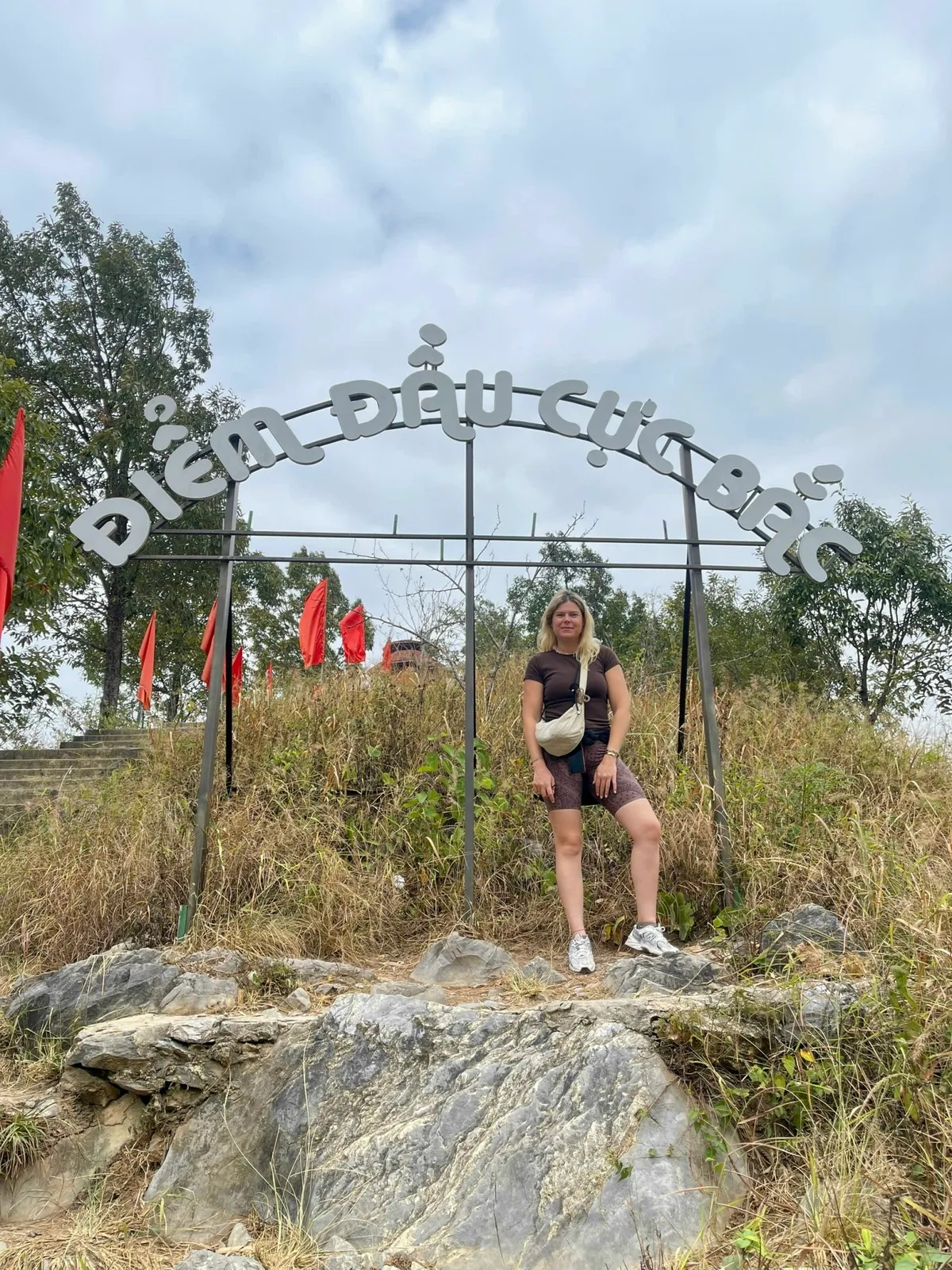 Guest standing under the Diem Dau Cuc Bac northernmost point sign near Lung Cu in Ha Giang