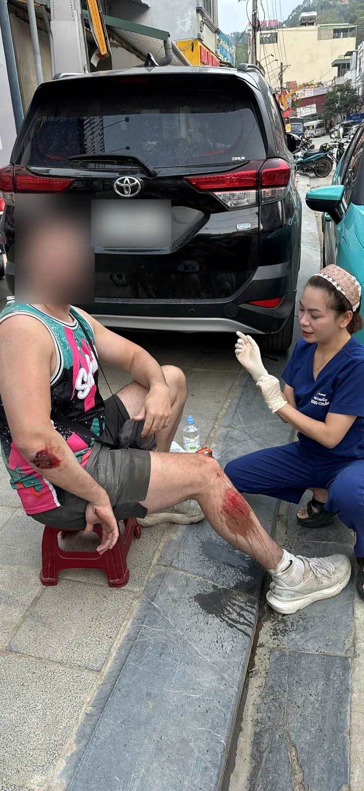 Freedom guest with grazed knee and elbow receiving first aid from a medical worker in Ha Giang, face blurred