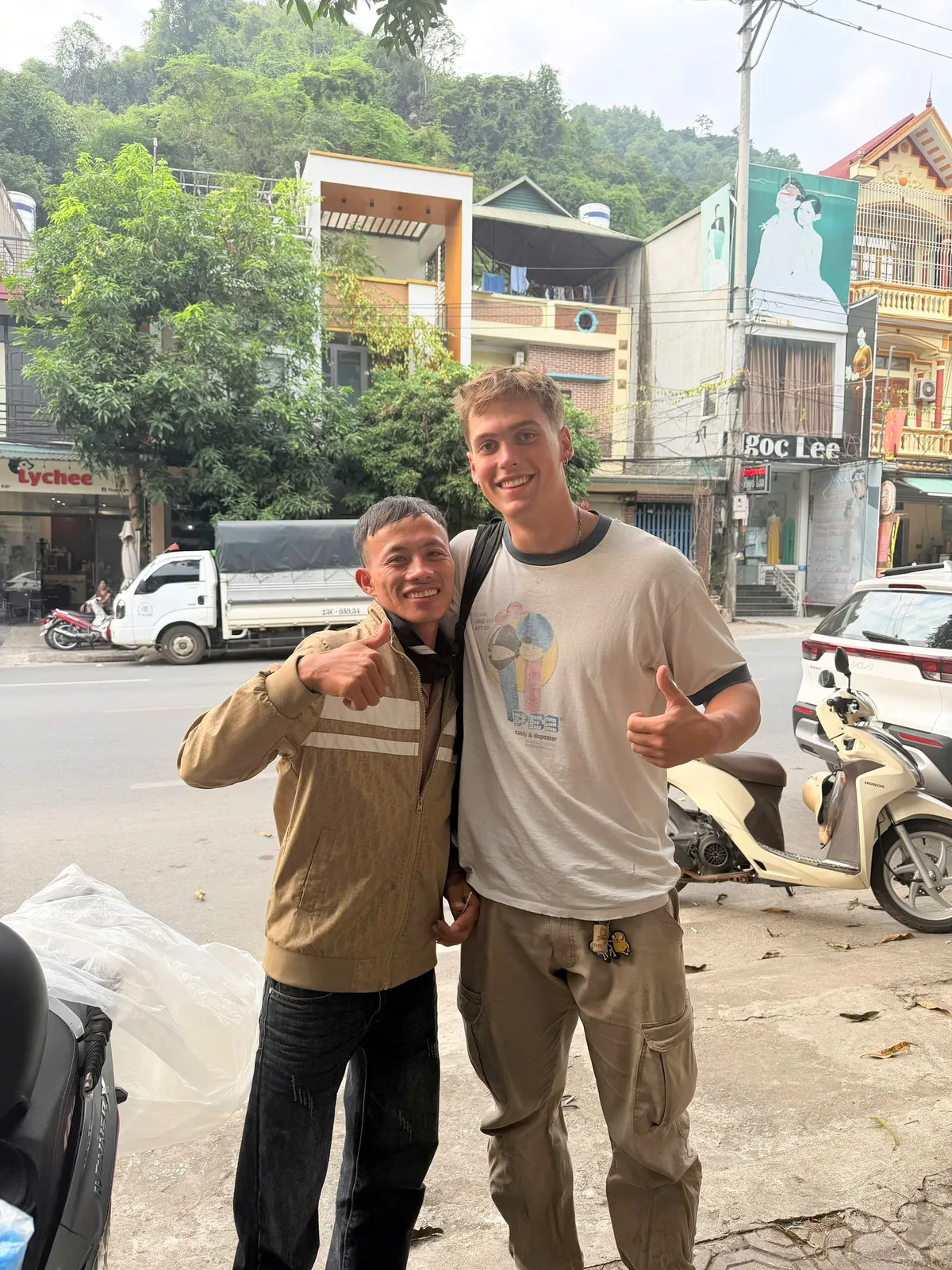 Smiling guest giving a thumbs up next to his Freedom Easy Rider driver on a street in Ha Giang