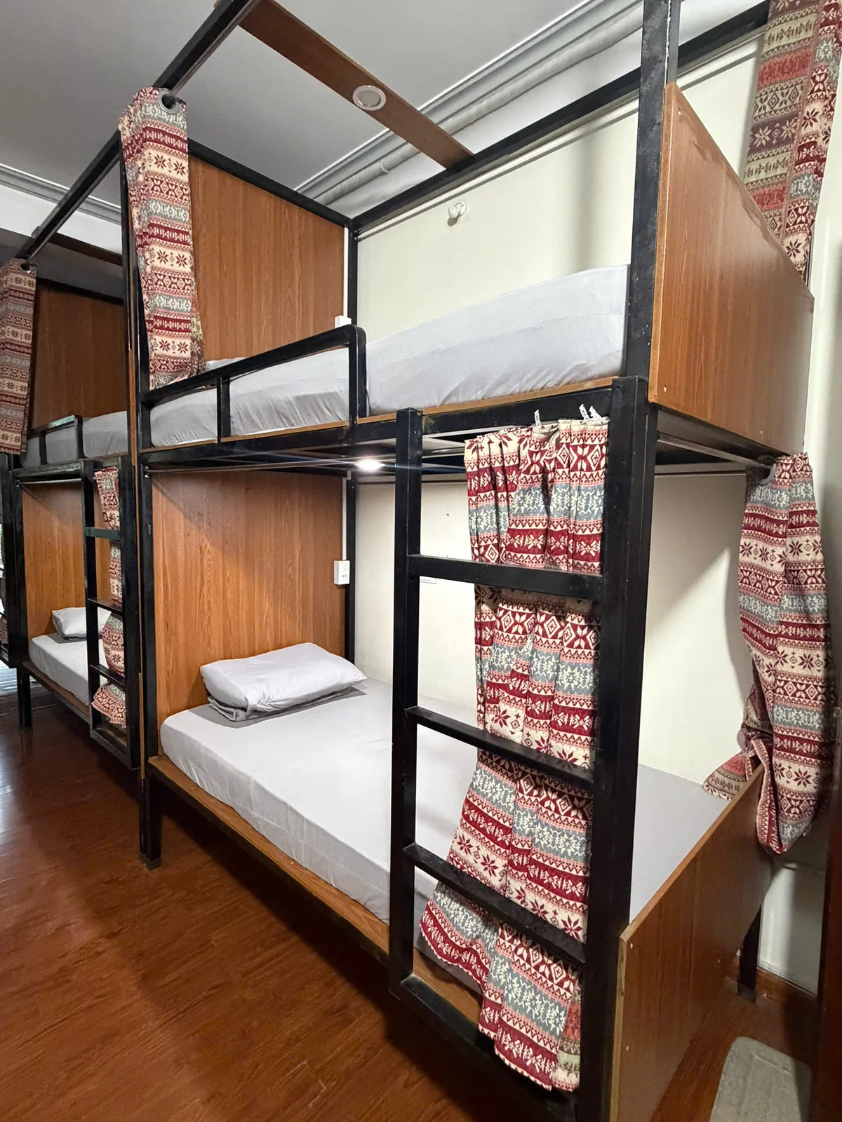 Curtained bunk beds with white sheets and reading lights in the Freedom hostel dorm in Ha Giang city